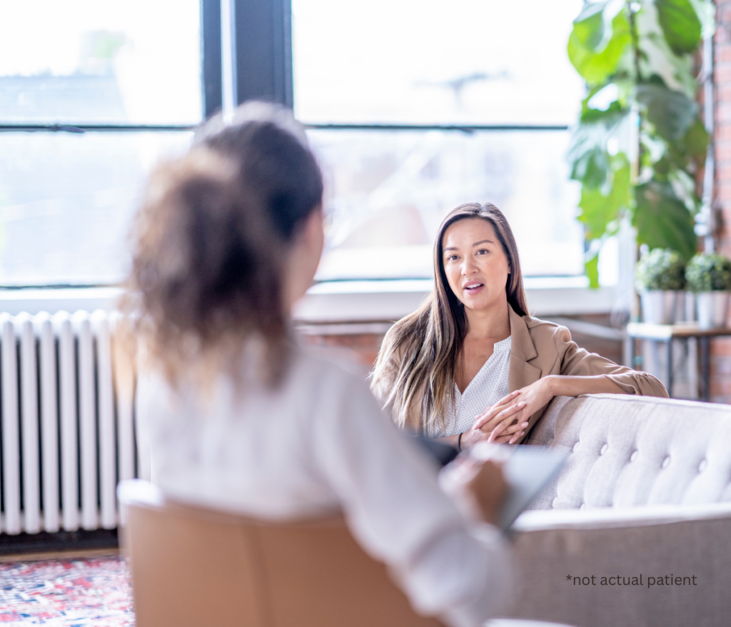 a woman sitting on a couch talking to a woman sitting in a chair
