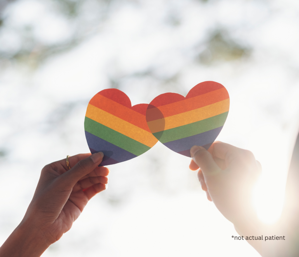 two hands holding rainbow hearts in the sunshine
